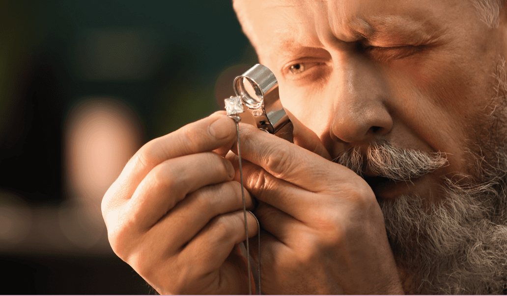 Goldschmied prüft Ring mit Lupe in der Werkstatt
